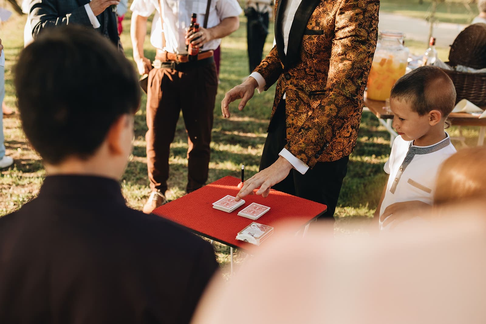 Manos de Alexander Main mostrando cartas sobre una mesa roja entre los asistentes